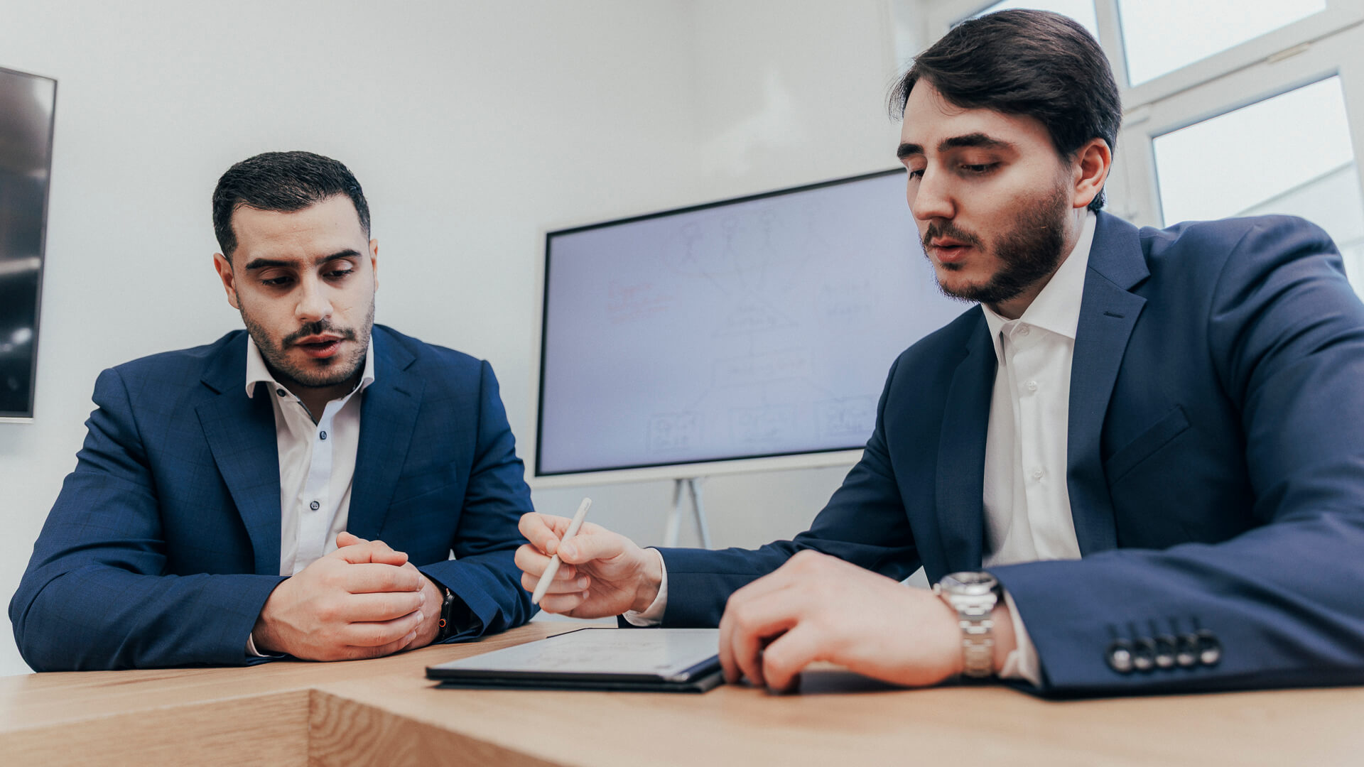 Zwei Steuerberater aus Siegen über ein Tablet gebeugt im Gespräch